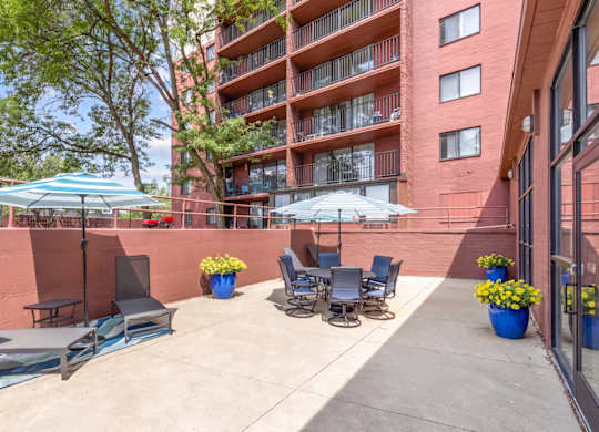 A patio with chairs and umbrellas is in front of a red building.