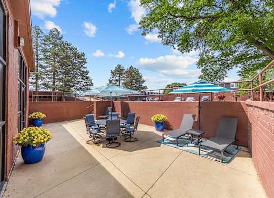 A patio with chairs and a table with flowers.