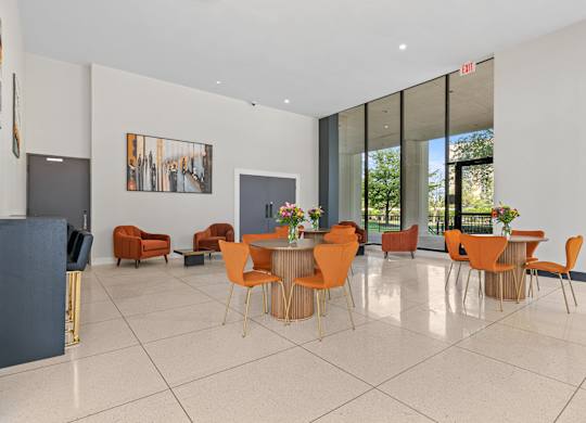 A room with orange chairs and a dining table.