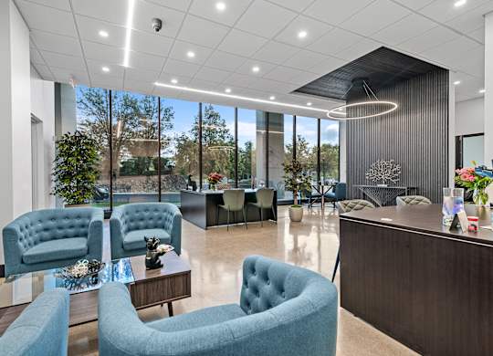 A modern office lobby with blue chairs and a reception desk.