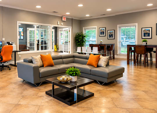 A spacious living room with a grey sofa, orange chairs, and a coffee table.