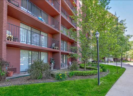 A red building with balconies and a lamp post on the sidewalk.