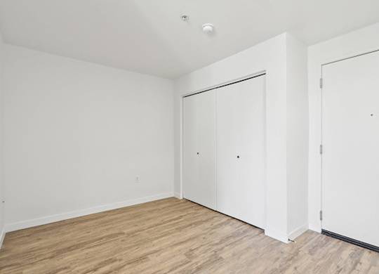 A room with white walls and wooden flooring with two doors.