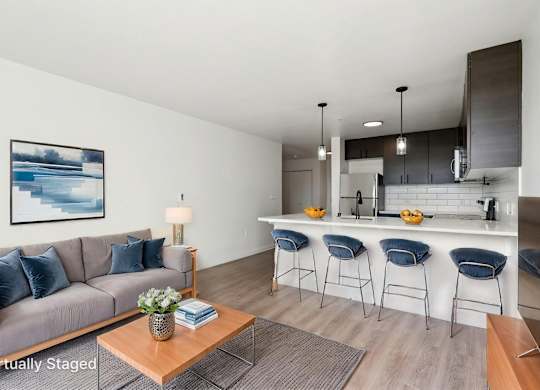 A living room with a grey couch and a coffee table with a vase of flowers on it.