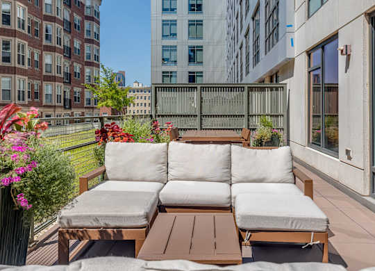 A wooden outdoor sofa with cushions is on a patio.
