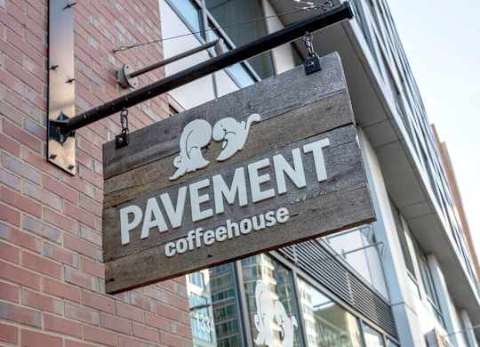 A wooden sign hanging from a building that says