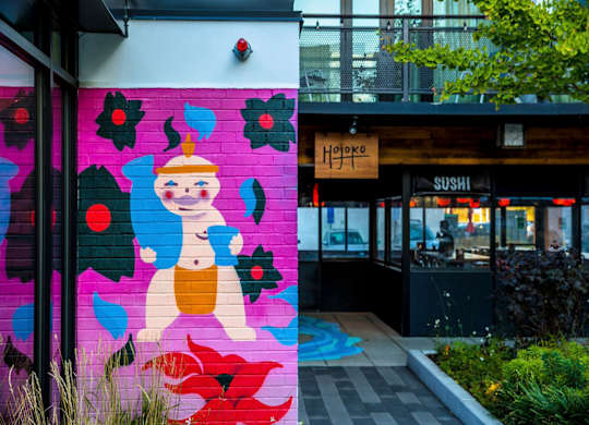 A mural of a smiling Buddha is painted on a wall.