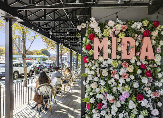 A restaurant with a flower wall and the name MIDA on it.