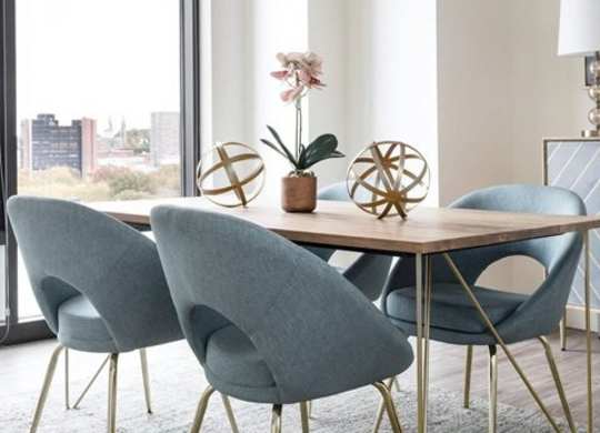 A dining table with grey chairs and a vase with a flower on it.