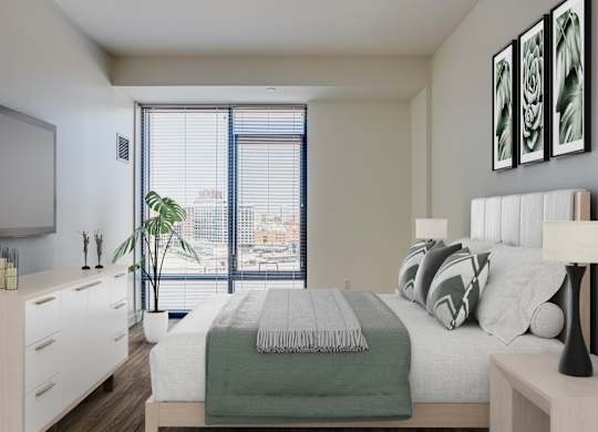 A bedroom with a bed, nightstand, and a window overlooking a cityscape.