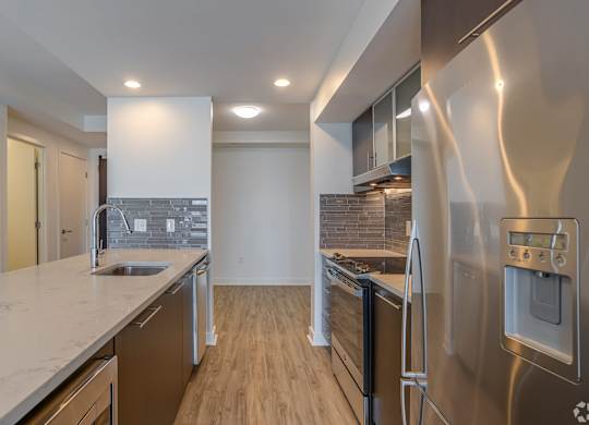 A modern kitchen with stainless steel appliances and wooden flooring.