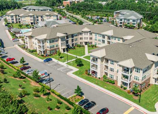 A large apartment complex with a parking lot in front.