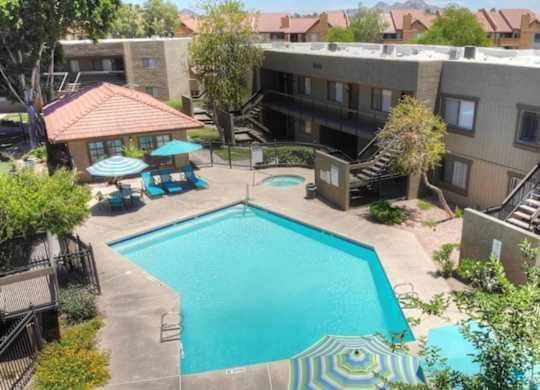 A swimming pool surrounded by a patio area with a table and chairs.