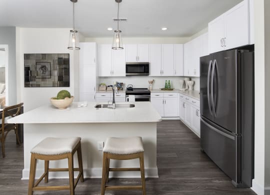 a kitchen with white cabinets and a large island with two stools