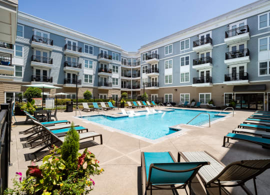 an apartment building with a swimming pool and lounge chairs