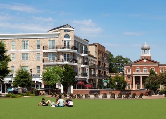 people sitting on the lawn in front of buildings on a sunny day