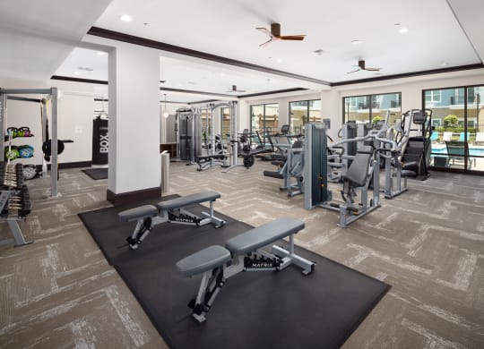 a gym with weights and cardio equipment in a building with windows