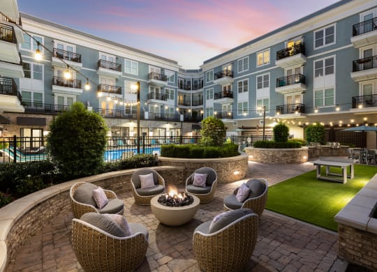 an outdoor patio with chairs and a fire pit at dusk