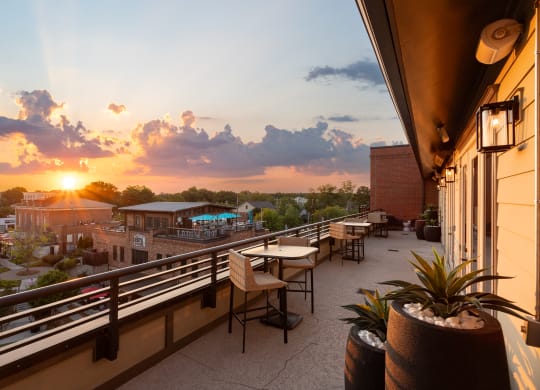 a rooftop terrace with tables and chairs and a sunset