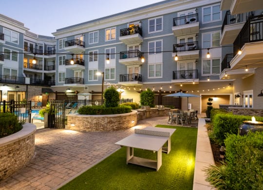 a courtyard with a table and benches in front of an apartment building