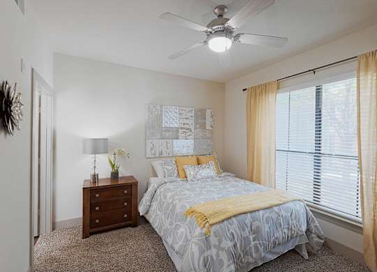 A bedroom with a bed, nightstand, and window.