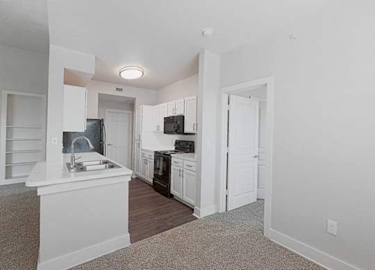 A kitchen with white cabinets and a black fridge.