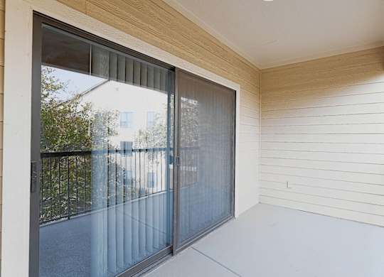 A sliding glass door with a black frame and a view of a street and buildings outside.
