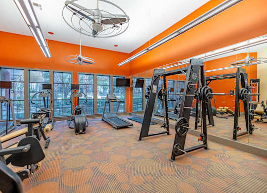 A gym with orange walls and a variety of exercise equipment.