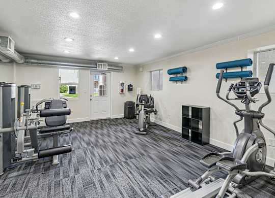 A spacious gym with a variety of equipment including treadmills, stationary bikes, and weight machines.