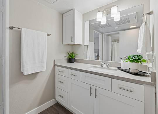 A white bathroom with a mirror, sink, and towel rack.