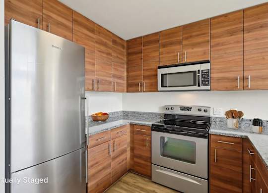 A kitchen with wooden cabinets and a stainless steel refrigerator.