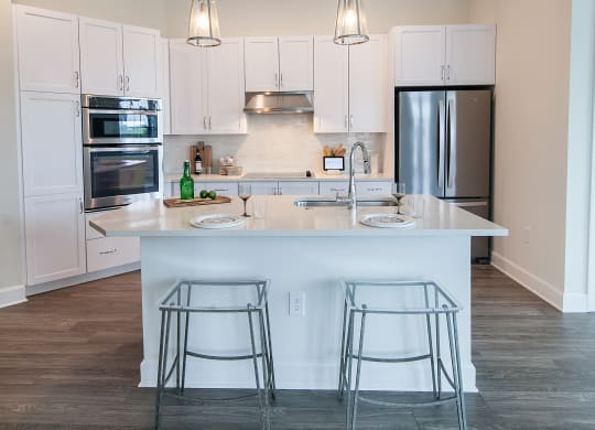 a kitchen with white cabinets and a large island with three bar stools