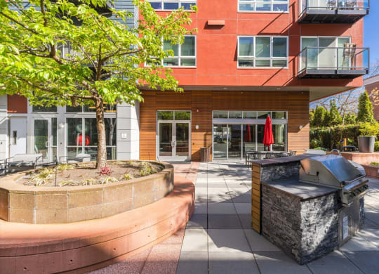 an outdoor patio with a bbq and a fire pit in front of a red building