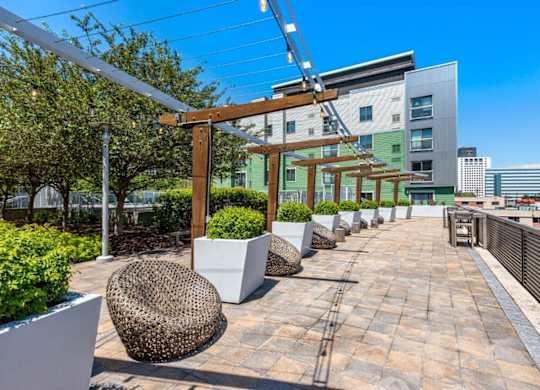 A rooftop patio with a woven chair and a white planter.