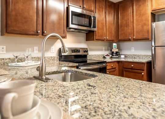 A kitchen with brown cabinets and granite countertops.