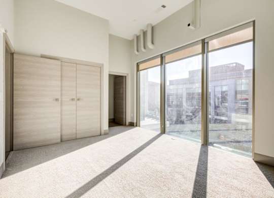 A room with a carpeted floor, a sliding glass door, and a wall-mounted air conditioning unit.
