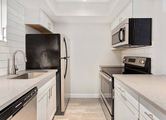A black refrigerator stands next to a sink in a kitchen.