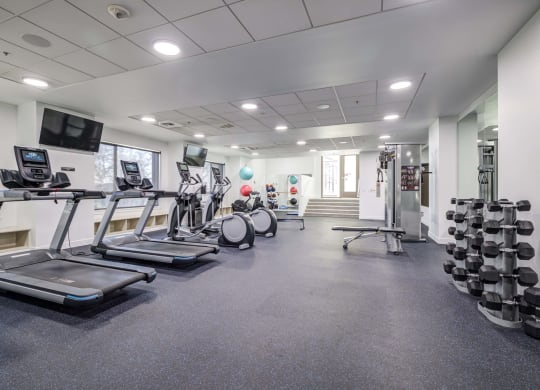 a gym with treadmills and other exercise equipment in a building with windows