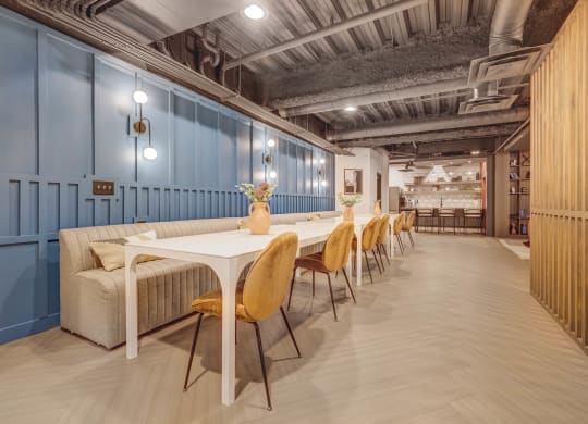a long dining room with blue walls and a long table with yellow chairs