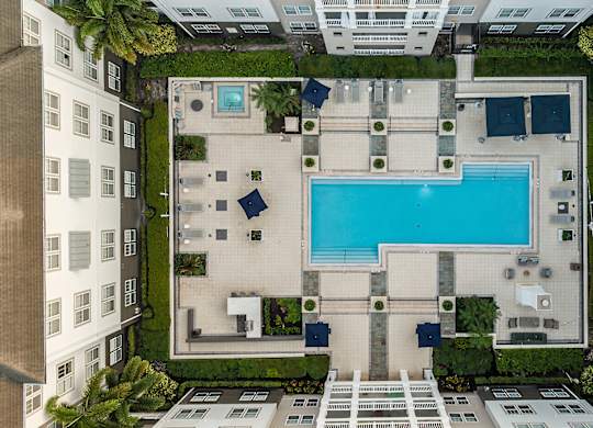 A swimming pool is surrounded by a patio and a small garden.