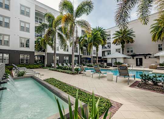 A pool surrounded by palm trees and chairs.