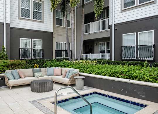 A pool in a backyard with a couch and a table.