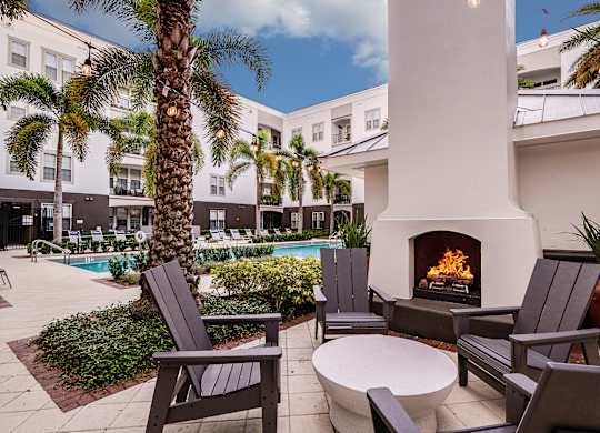 A patio with a fireplace, chairs, and a table.