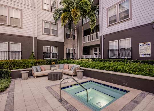A pool surrounded by a patio and a building.