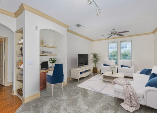 a living room with white furniture and a ceiling fan
