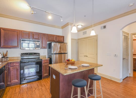 a kitchen with an island with stools and a stainless steel refrigerator
