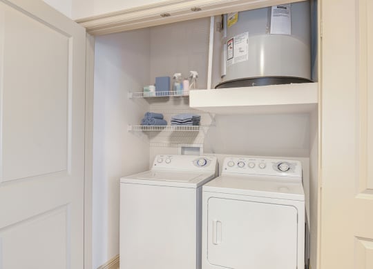 a small laundry room with a white washer and dryer and a shelf above