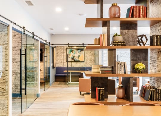 a living room with a table and shelves with books at 100 House Apartments, Jersey City , New Jersey