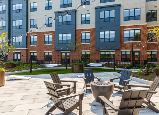 an outdoor patio with chairs and a fire pit in front of an apartment building at 100 House Apartments, Jersey City