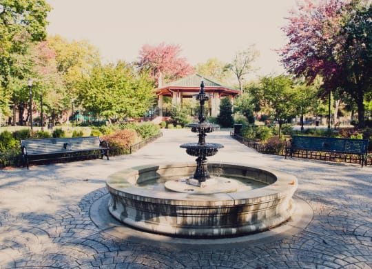 a fountain in a park with benches and a gazebo at 100 House Apartments, New Jersey, 07310